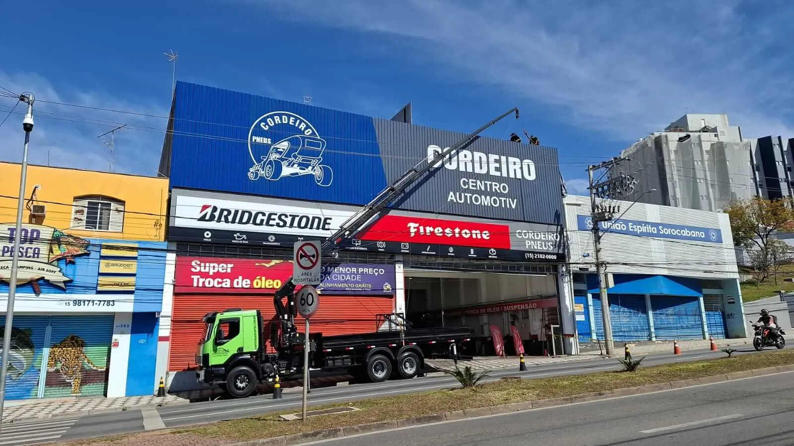 Caminhão munck instalando fachada em centro automotivo